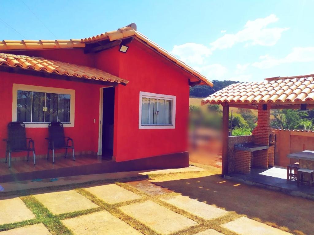 卡皮托利乌Acomodação chalé entre capitolio e escarpas do lago的红色的房子,设有庭院和桌子