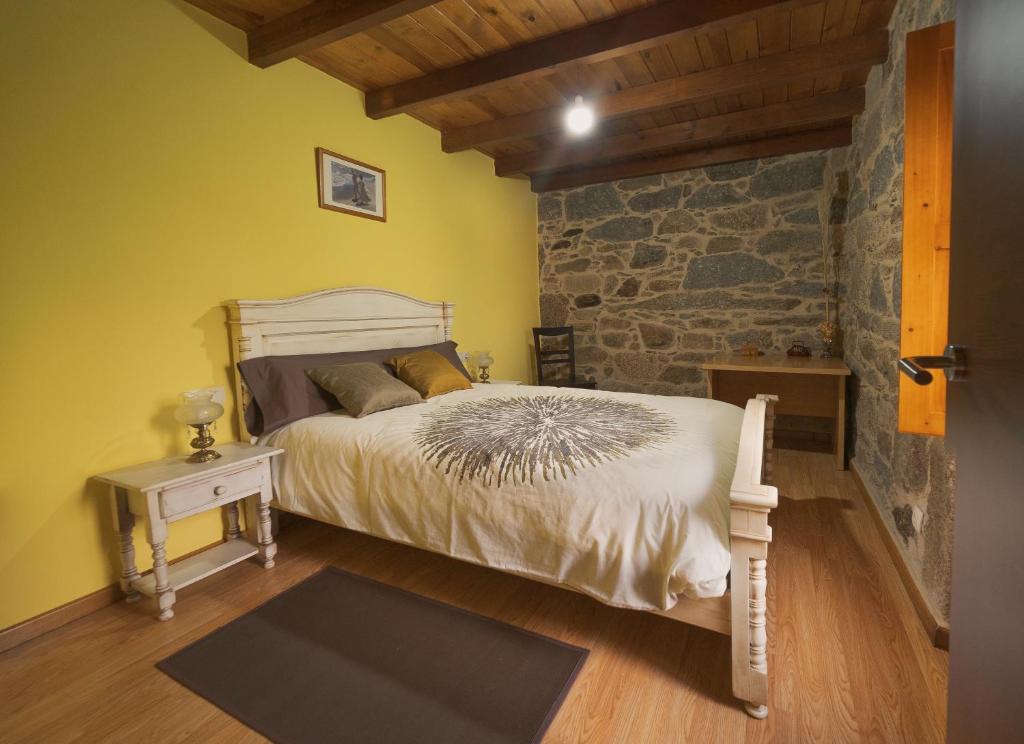 庞特维德拉A Casa da Charca - Casa rural con jardín的一间卧室设有一张床和石墙