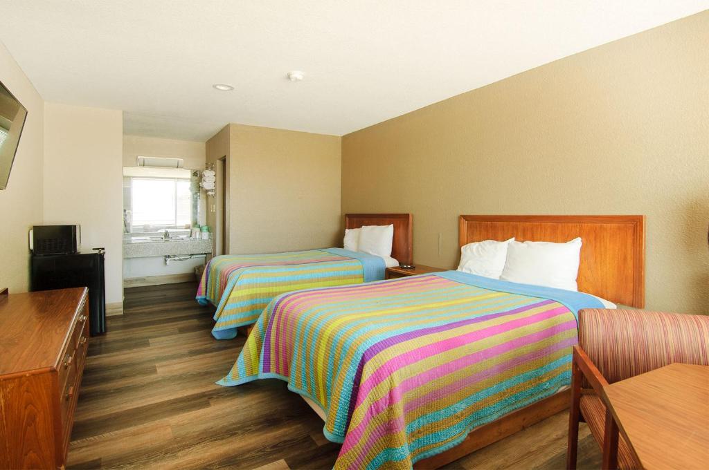 罗杰斯Town and Country INN的酒店客房设有两张床和一张桌子。
