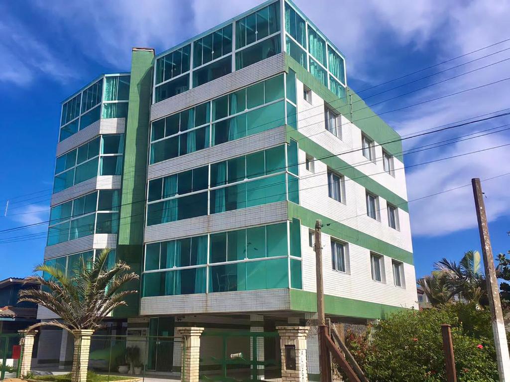 特拉曼达伊Tropical Tramandaí的一座高大的绿色和白色建筑,拥有棕榈树