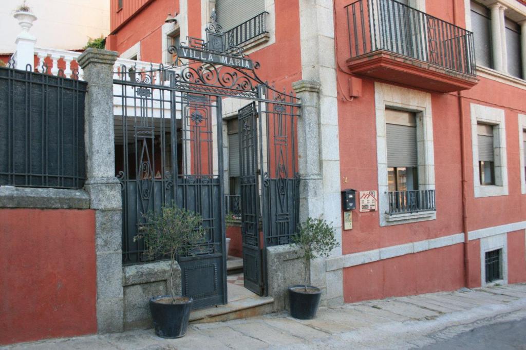 Fuentes de BéjarHotel Villa Maria的一座红色的建筑,有黑色的大门和盆栽植物