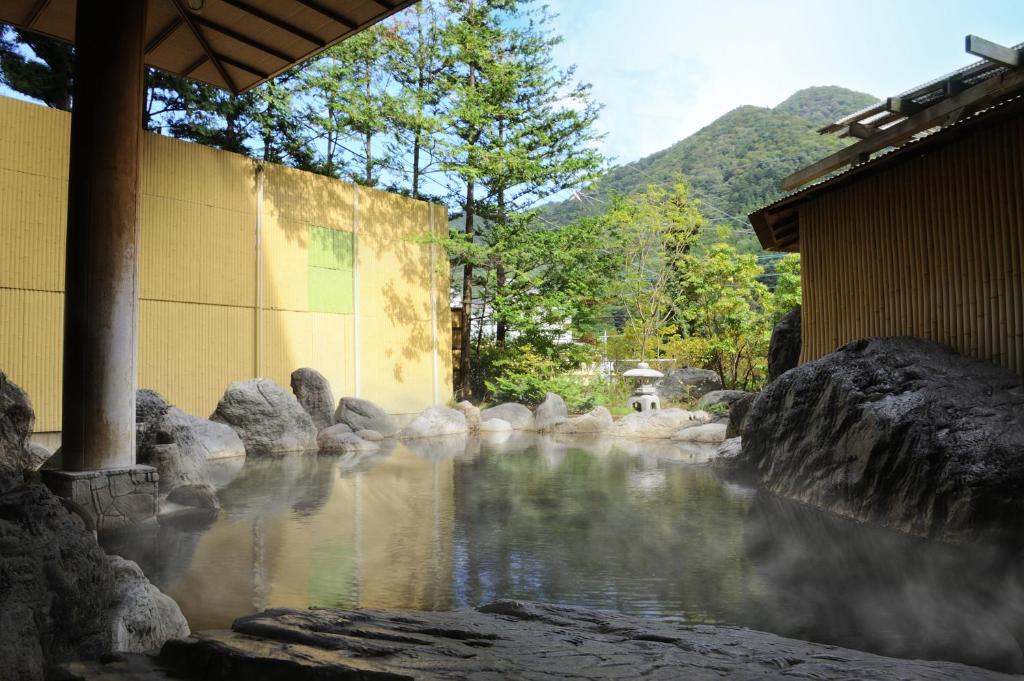 那须盐原市Shiobara Onsen Yashio Lodge的靠近建筑物和岩石的水流