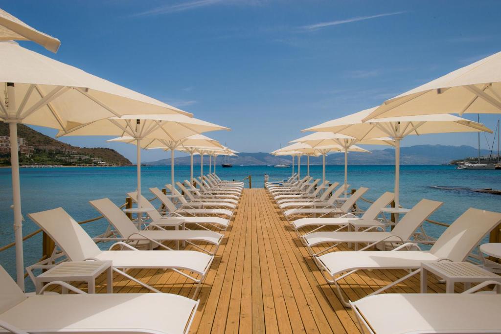 阿克亚拉尔Bellazure Hotel的码头上一排白色的椅子和遮阳伞