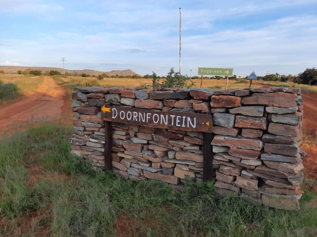 克拉多克Doornfontein Guest Farm的路中间有标志的石墙