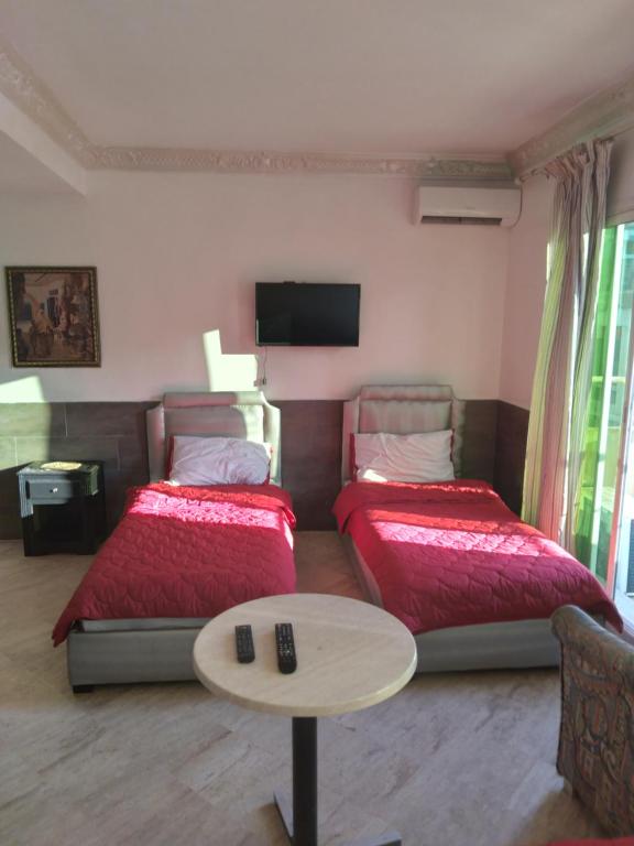 卡萨布兰卡SINGAPOUR MAROC的客房设有两张床、一张桌子和一台电视机。