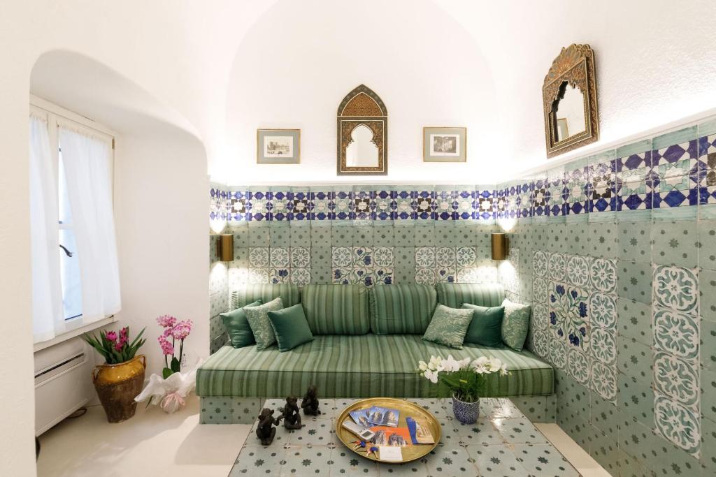 卡普里Qasar Luxury Suite - in Capri's Piazzetta的客厅配有绿色沙发以及蓝色和白色瓷砖
