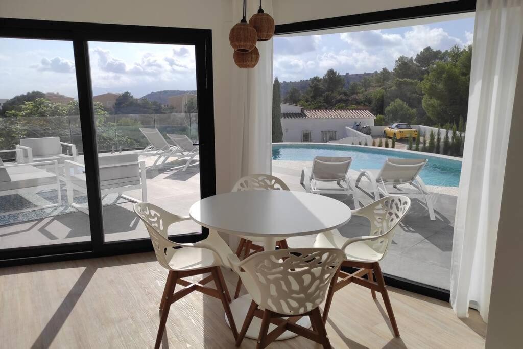 库姆布勒德尔索尔Precioso apartamento en una villa con piscina en Cumbre del Sol Moraira Benitachell的一个带游泳池的房间,配有一张白色的桌子和椅子