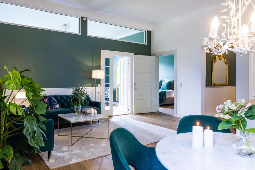 Augustenborg'Gem Suites Luxury Holiday Apartments的客厅配有绿色椅子和桌子