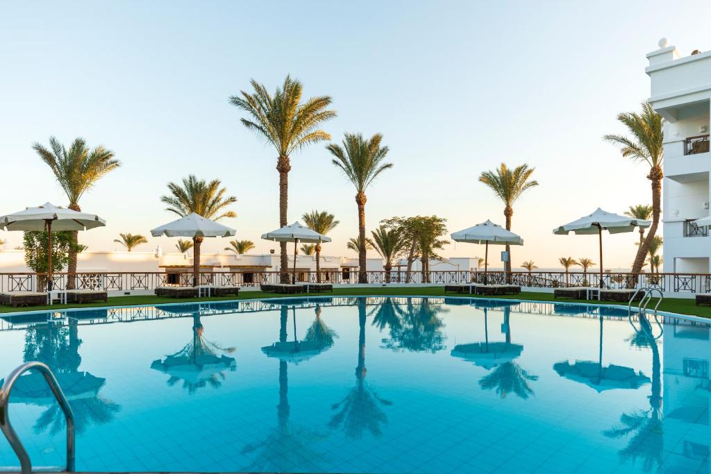 沙姆沙伊赫Sunrise Remal Beach Resort的棕榈树游泳池以及酒店