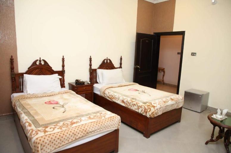 木尔坦Hotel OR Odyssey Residence的一间卧室配有两张床和电视。