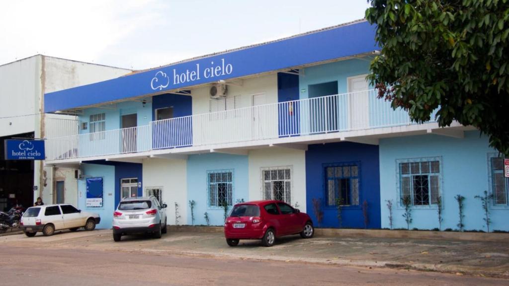 波多韦柳Hotel Cielo的一座蓝色的建筑,前面有汽车停放