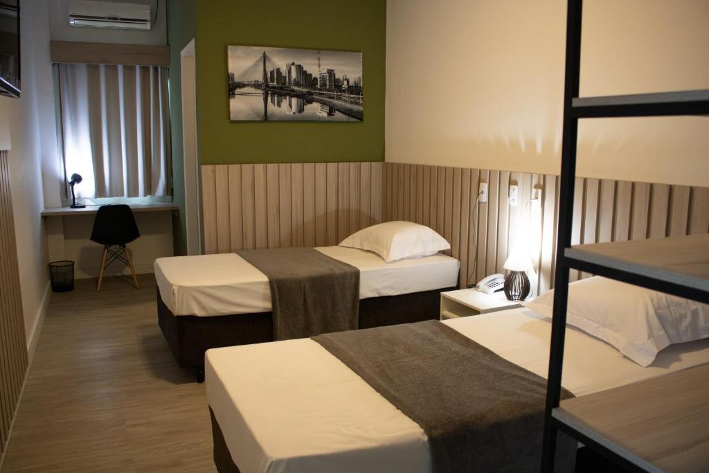 圣若泽杜斯坎普斯Hotel Jardim Sul的酒店客房设有两张床和窗户。