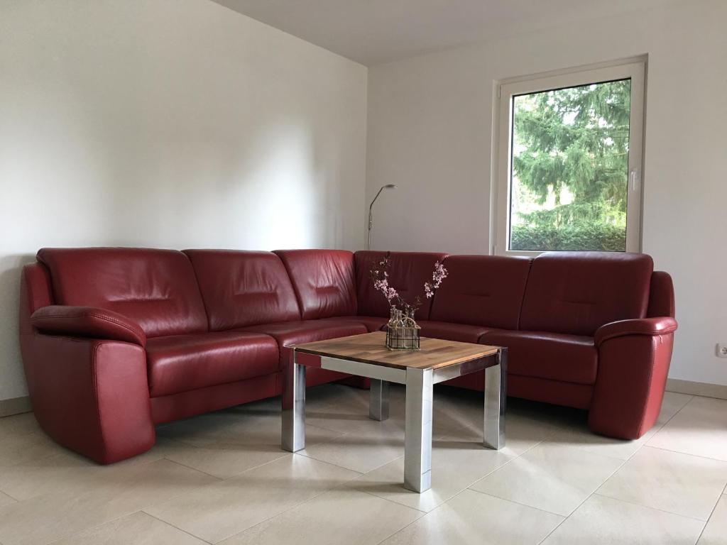 波茨坦FERIENHAUS POTSDAM BERLIN GÄSTEHAUS MONTEURZIMMER SEENÄHE的客厅里一张红色的沙发,配有桌子