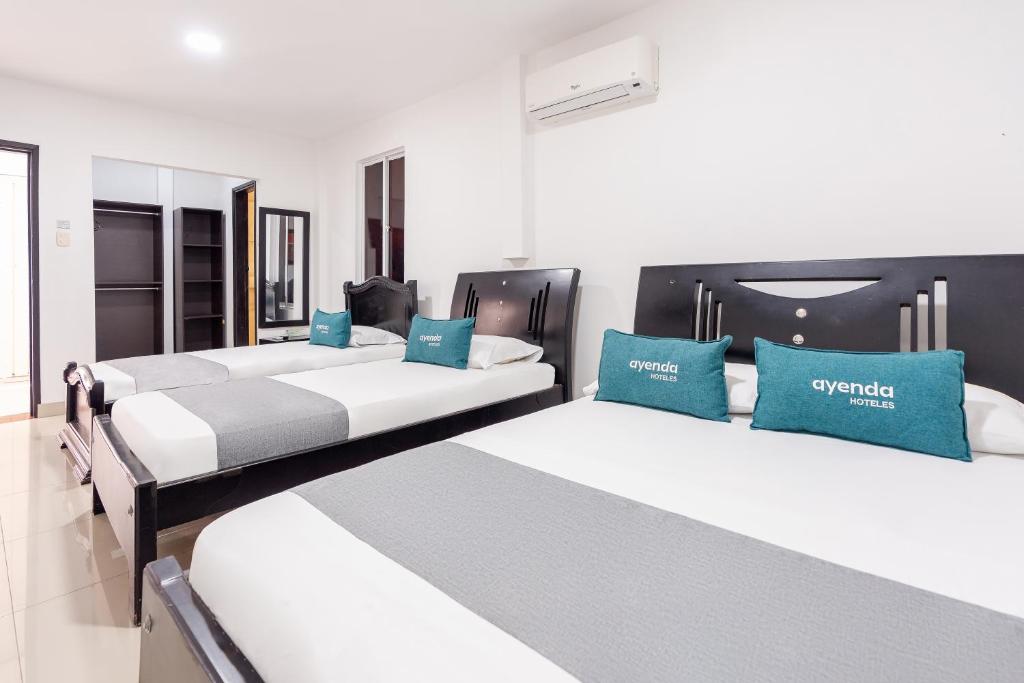 巴耶杜帕尔Ayenda Union的配有蓝色枕头的客房内的三张床