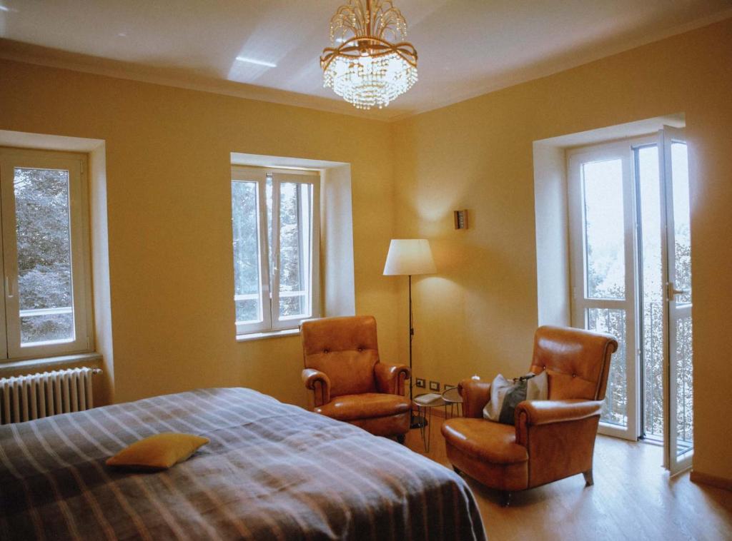 PettinengoLa Foresteria di Villa Piazzo的一间卧室配有两把椅子、一张床和一个吊灯。