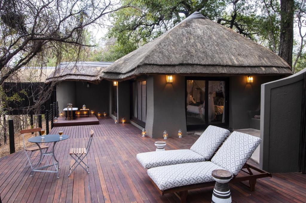 斯库库扎Jock Safari Lodge的一个带椅子和茅草屋顶的大甲板