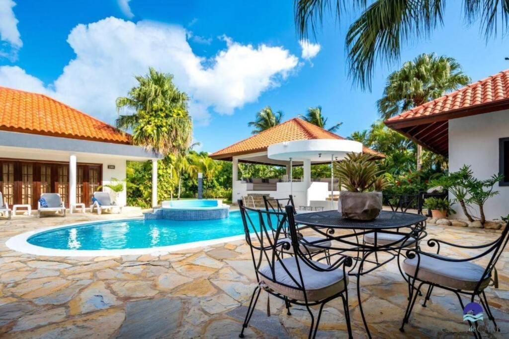 拉罗马纳Luxury Villa Casa De Campo的游泳池旁带桌椅的天井