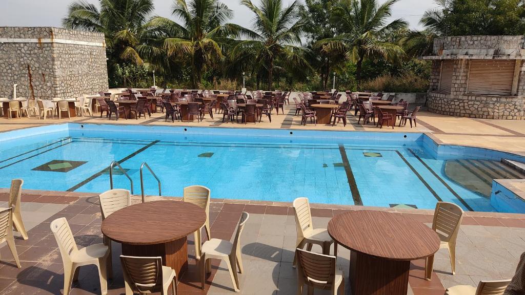BāgalkotKanthi Resorts Badami的餐厅旁的带桌椅的游泳池