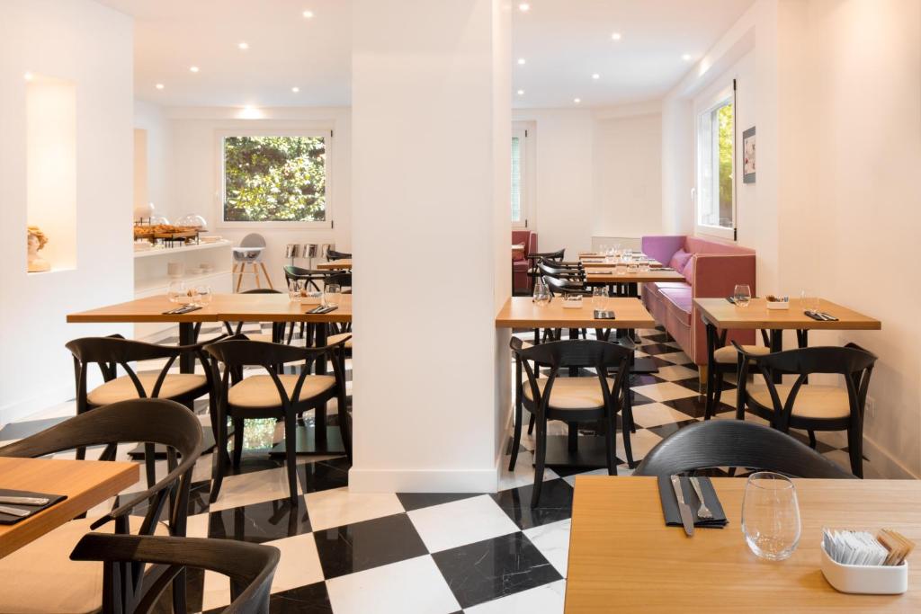 米兰Hotel Morfeo的餐厅设有木桌和椅子,铺有 ⁇ 木地板