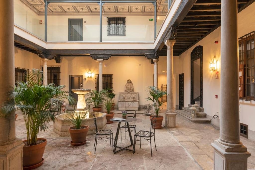 格拉纳达Palacete 1620, Premium Suites, Only adults的建筑中带椅子和植物的庭院