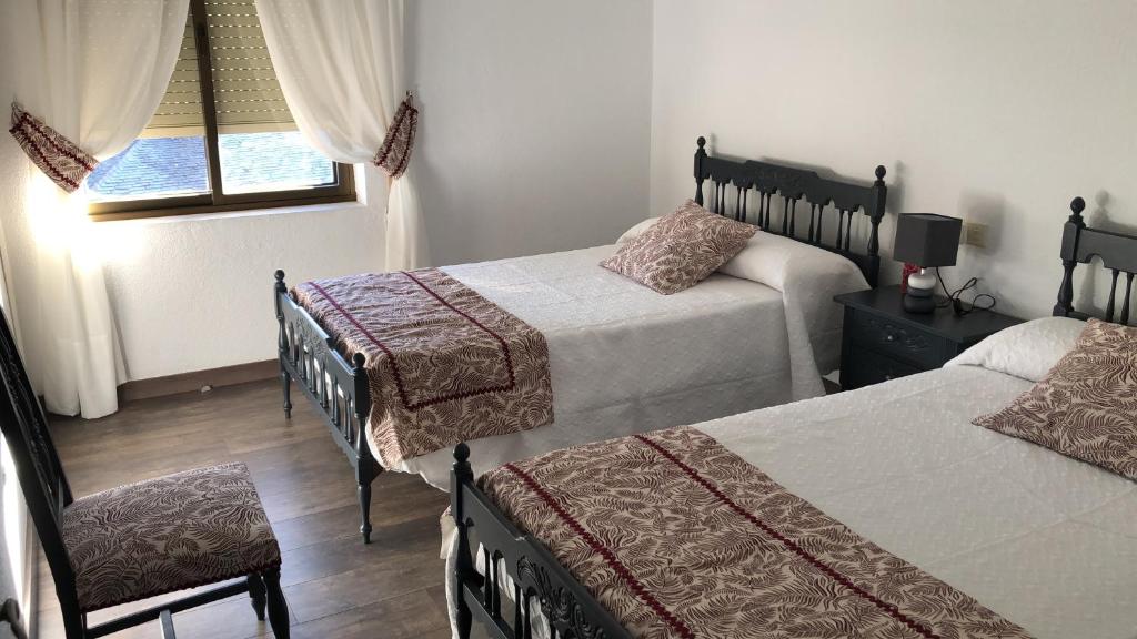 普韦布拉桑纳比亚El Mirador de la Villa的一间卧室设有两张床、一把椅子和一个窗户。
