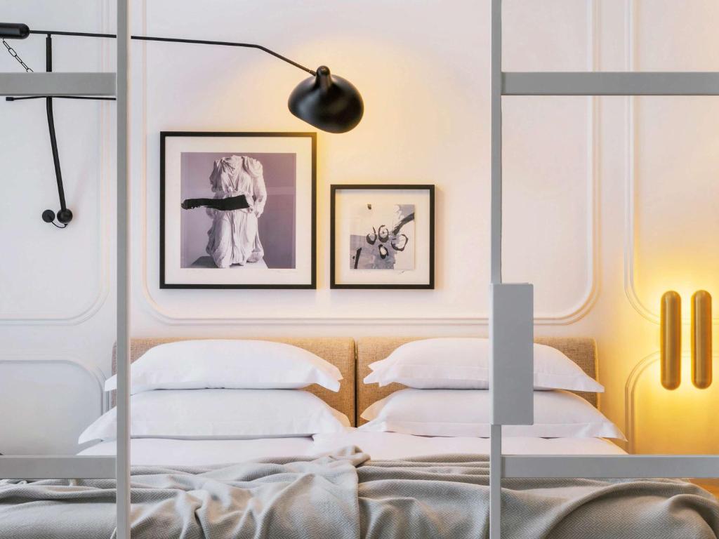斯普利特Heritage Hotel FERMAI MGallery Split的卧室配有一张墙上有两张照片的床。