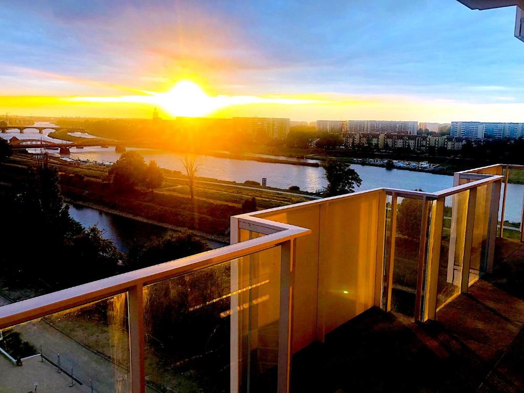 弗罗茨瓦夫Apartament z tarasem i widokiem na Odrę的从大楼的阳台上可欣赏到日落美景