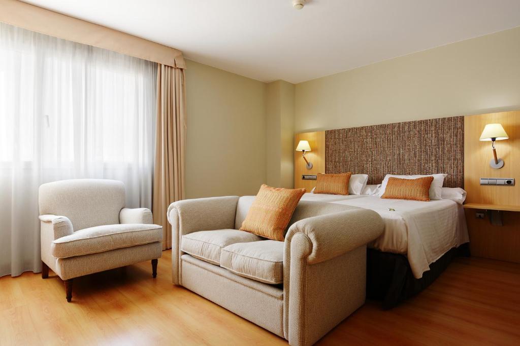 萨拉戈萨U Hotel Villa-Gomá的配有一张床和一把椅子的酒店客房