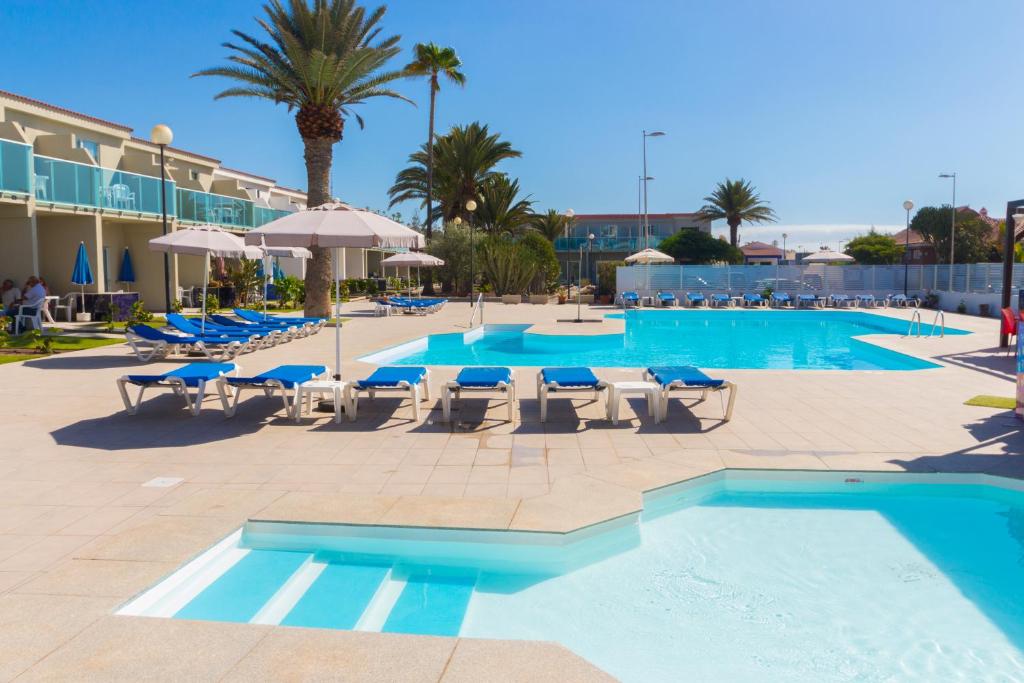 英格兰海滩科林托2简易别墅旅馆的一个带躺椅和遮阳伞的大型游泳池