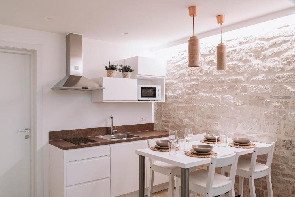 莫尔费塔INDE Á LA TERRE, GUEST HOUSE Locazione Turistica的厨房配有白色橱柜和白色的桌椅