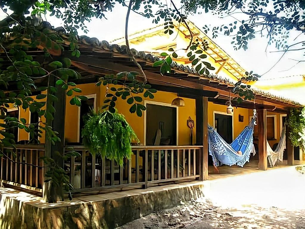 皮帕Casa Cajueiro em Pipa的黄色房子,外面设有门廊和吊床