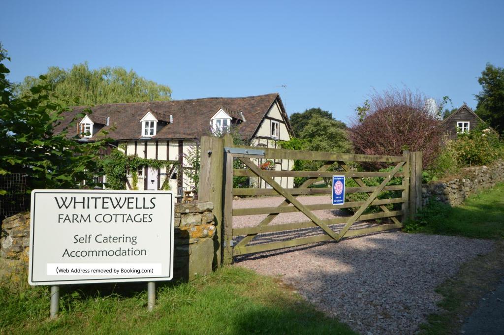 大莫尔文Whitewells Farm Cottages的房屋前有标志的大门