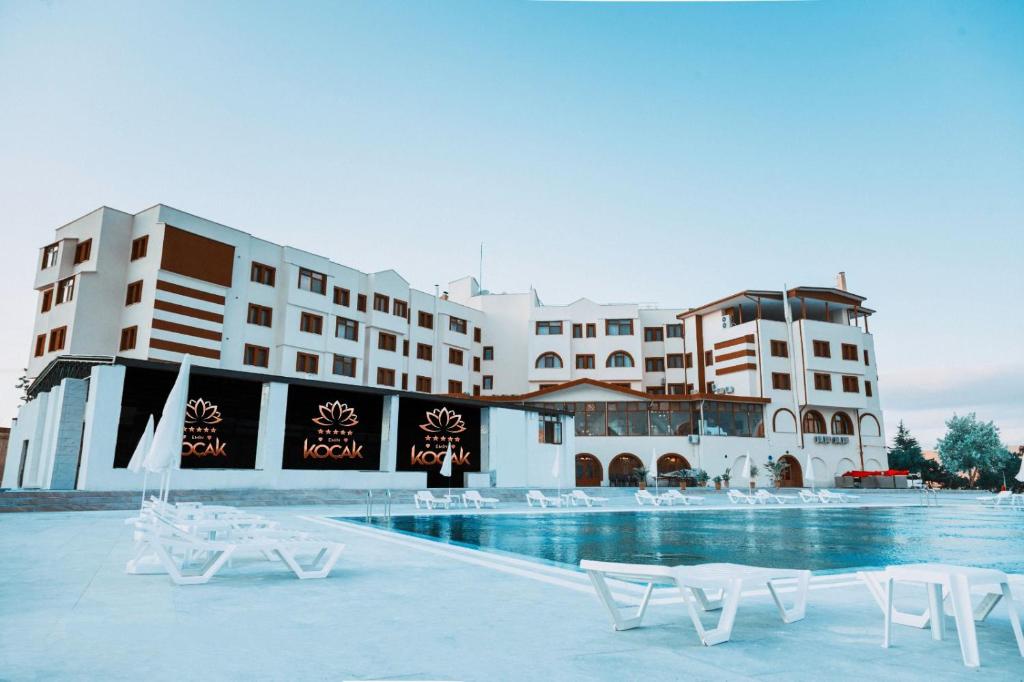 内夫谢希尔Emin Koçak Hotel Kapadokya的酒店拥有游泳池和白色椅子