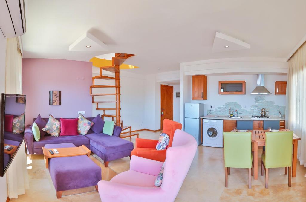 卡斯Çınarlar Apart Hotel KAŞ的客厅配有紫色沙发和五颜六色的椅子