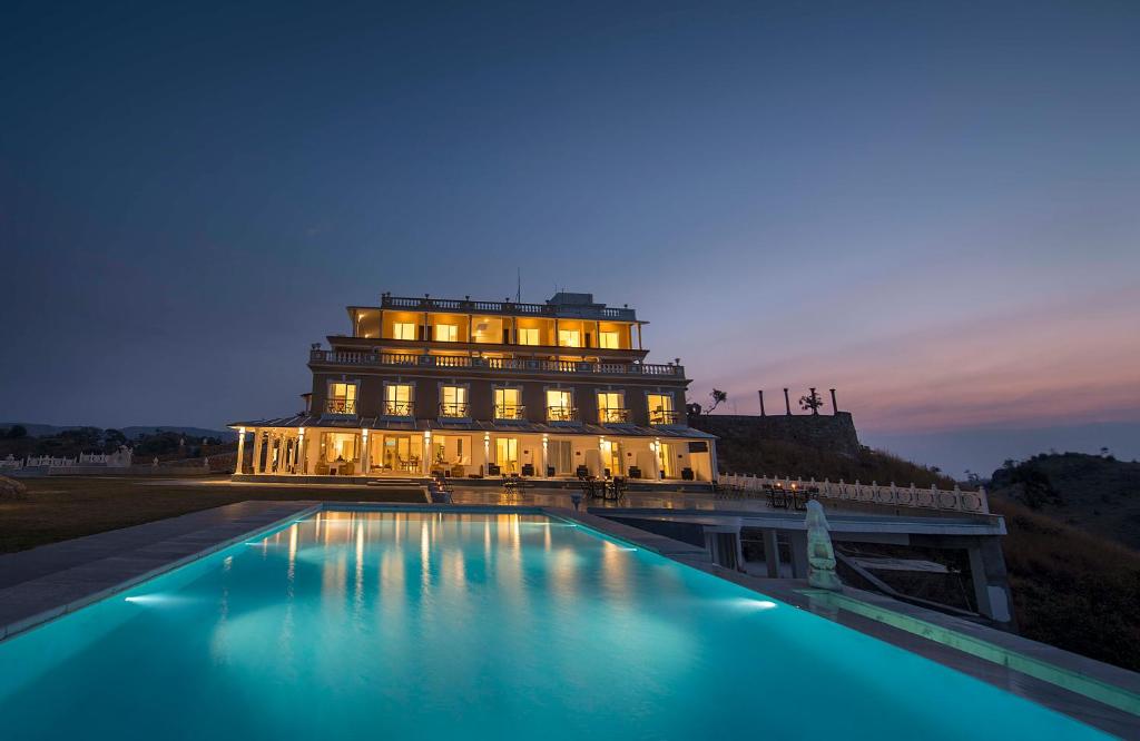 贡珀尔格尔Fateh Safari Resort by Fateh Collection的一座建筑,在晚上前方有一个游泳池