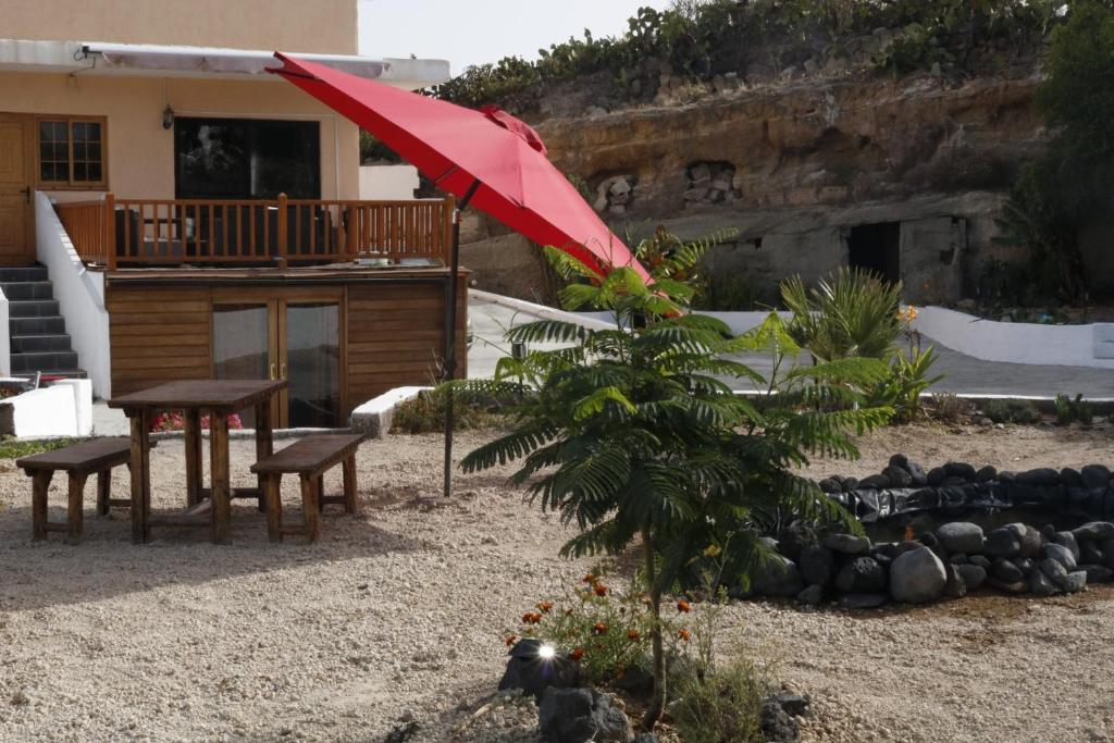 FasniaHalf wooden rural apartment的一个带桌子和红色遮阳伞的庭院