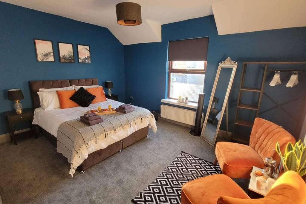 佩恩顿Modern and Spacious 4 Bedroom House, Hot Tub, Wifi, Netflix, Parking的一间卧室拥有蓝色的墙壁,配有一张带橙色枕头的床。
