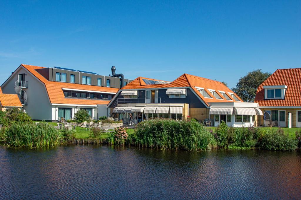 德科赫Landgoed Hotel Tatenhove Texel的一座有橙色屋顶的建筑,毗邻水体
