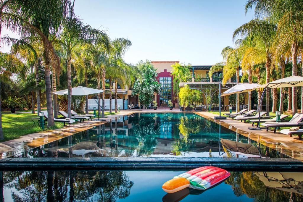 马拉喀什Palais Mirage d'Atlas - Restaurant & Spa & Day Pass的棕榈树游泳池及度假村