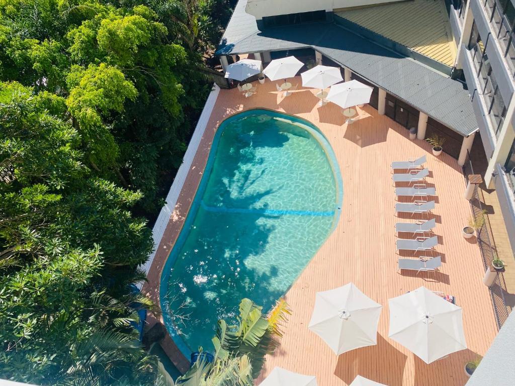 黄金海岸Greenmount Beach House的享有带遮阳伞和椅子的游泳池的顶部景致
