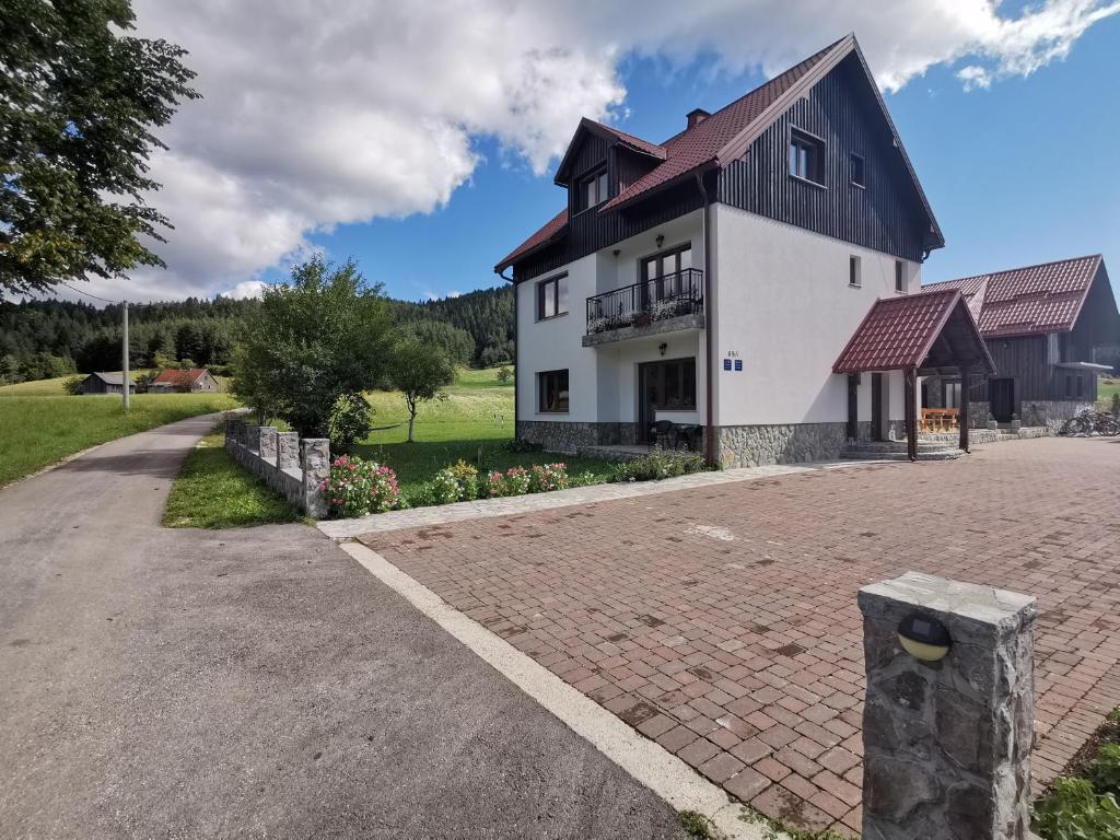 Gornji Babin PotokPlitvice Antico的白色的房子,有黑色的屋顶和砖砌车道