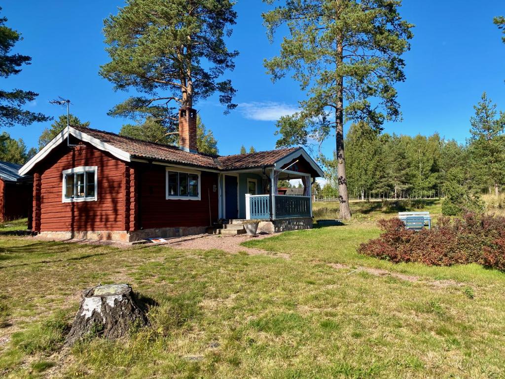 奥萨Hansjö stugby - Topersvägen的一座红色的小房子,在院子里设有门廊