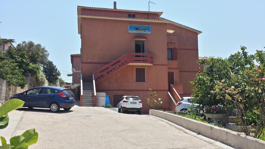 马达莱纳Guest House Tra Rocce E Mare的两辆车停在大楼前的建筑物