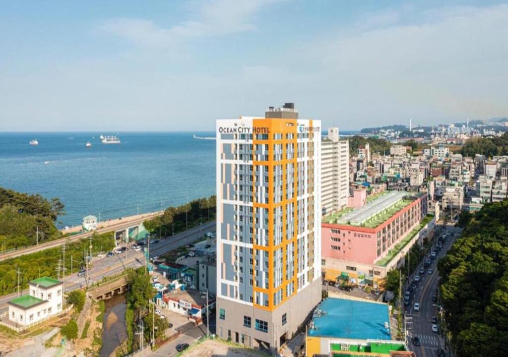 东海市Donghae Oceancity Residence Hotel的一座高大的黄色和白色建筑,毗邻大海
