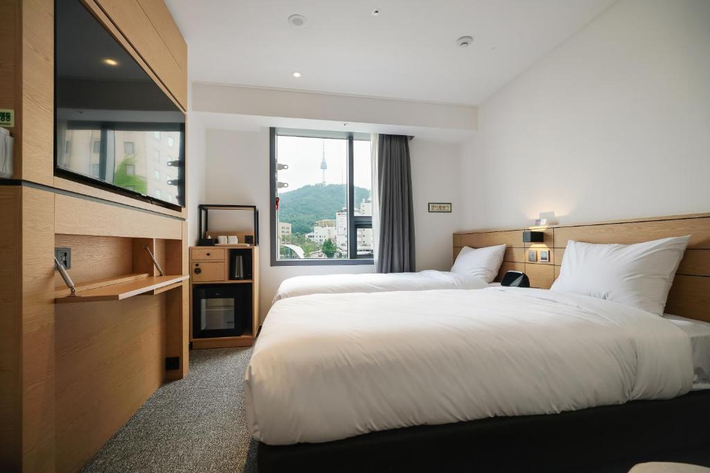 首尔Henn na Hotel Seoul Myeongdong的酒店客房设有两张床和窗户。