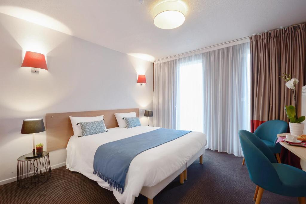 里尔Appart'City Confort Lille Grand Palais的酒店客房带大床和蓝椅