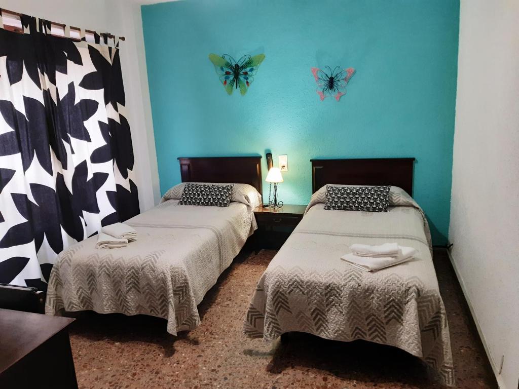 奥利瓦橙花酒店的墙上有蝴蝶的房间的两张床