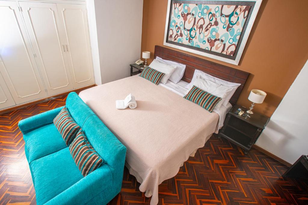 皮乌拉Posada Blanca Hotel Boutique的一间卧室配有一张大床和一张蓝色的沙发