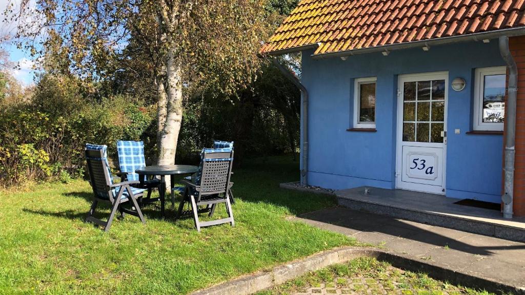 奥茨塞巴德·迪尔哈根-"Kleine Koje" Fewo im EG - Fischländerweg 53A的蓝色房子前面的两把椅子和一张桌子