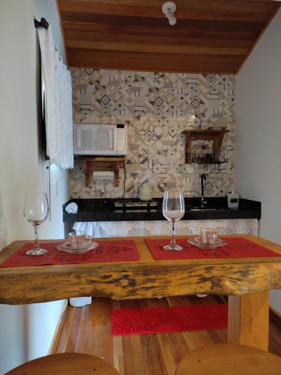 新文达移民镇Chalés Vale das Pedras的厨房配有木桌上的两杯酒杯